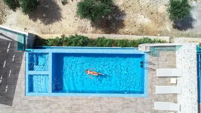 a person swimming in a large swimming pool at Nafsika Xenia - Alkinoos Villa in Plátanos