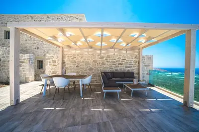 a wooden pergola with a table and chairs on a deck at Nafsika Xenia - Alkinoos Villa in Plátanos