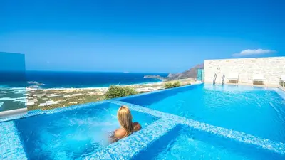 a woman in a swimming pool with a view of the ocean at Nafsika Xenia - Alkinoos Villa in Plátanos