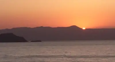 a sunset over the water with mountains in the background at Sunny family apartment in Chania close to the sea in Chania Town