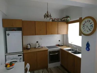 a kitchen with wooden cabinets and a clock on the wall at Sunny family apartment in Chania close to the sea in Chania Town