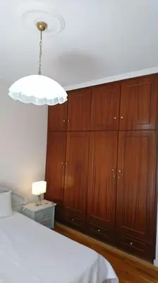 a bedroom with a bed and a chandelier and wooden cabinets at Sunny family apartment in Chania close to the sea in Chania Town