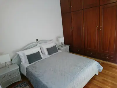 a bedroom with a large bed with wooden cabinets at Sunny family apartment in Chania close to the sea in Chania Town