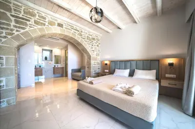 a bedroom with a large bed and a stone wall at Nafsika Xenia - Ariti Villa in Plátanos
