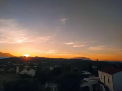 a sunset over a city with the sun setting at Giannis Traditional House in Vamos