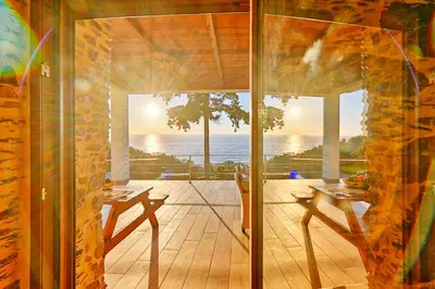 a room with a view of the ocean through a glass door at Metochi Seaview Holiday House in Ayía Paraskeví