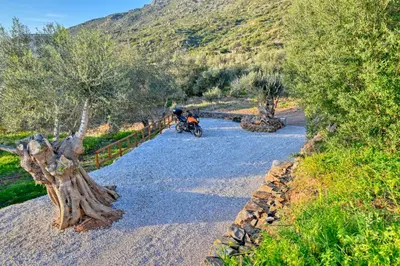 a person riding a motorcycle down a gravel road at Metochi Seaview Holiday House in Ayía Paraskeví