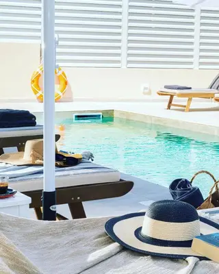 a hat sitting on a table next to a swimming pool at Meliora Suites in Drapaniás