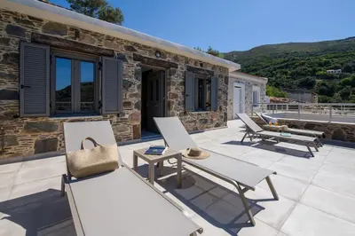a stone cottage with a patio with benches at Vigla Apartments No.3 in AmigdhalokeFálion