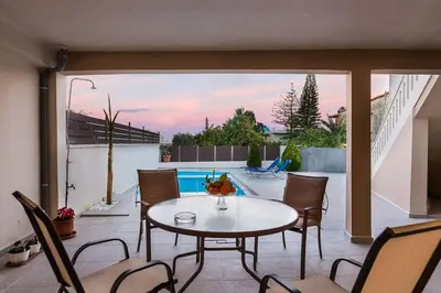 a patio with a table and chairs and a pool at Lefteris Holiday Home in Chania Town