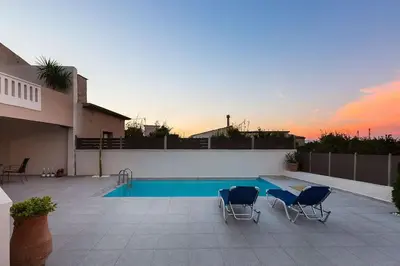 a swimming pool with two chairs next to a house at Lefteris Holiday Home in Chania Town