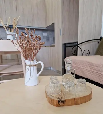 a coffee table with a vase and glasses on it at Granny's Nest in Kalyves