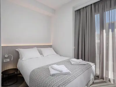 a white bedroom with a bed and a window at Casa D'Irene Apts in Chania Town