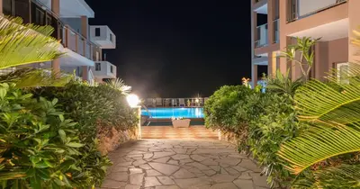 a walkway leading to a swimming pool at night at Cozy Corner VS Beachfront in Stalos