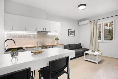 a white kitchen and living room with a couch at Nisos apartments, Chania center in Chania Town