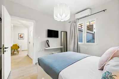 a white bedroom with a bed and a window at Nisos apartments, Chania center in Chania Town