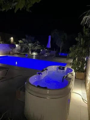 a jacuzzi tub sitting next to a pool at night at Amare suite in Perivólia