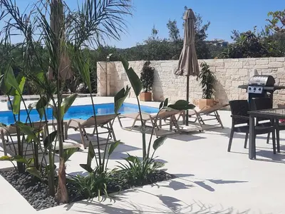 a patio with chairs and an umbrella next to a pool at Amare suite in Perivólia
