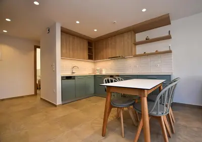a kitchen with blue cabinets and a table and chairs at Rosemary Apartments in Palaiochóra