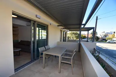 a table and chairs on the balcony of a house at Rosemary Apartments in Palaiochóra