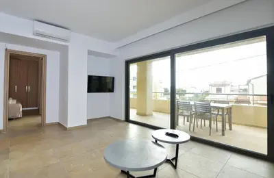 a living room with a table and a balcony at Rosemary Apartments in Palaiochóra