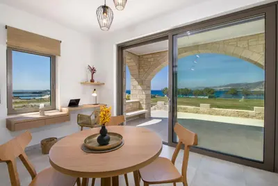 a dining room with a table and chairs and a large window at Christos Place-Paleochora in Palaiochóra