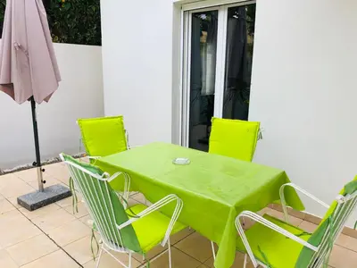 a green table and chairs on a patio with an umbrella at Stamatias Home, fully equipped cottage 5 minutes from the sea in Chania Town