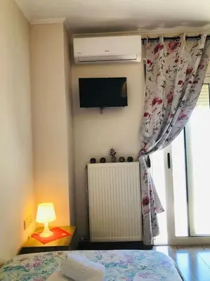a bedroom with a bed and a tv and a window at Ariadni's apartment 1 in Chania Town