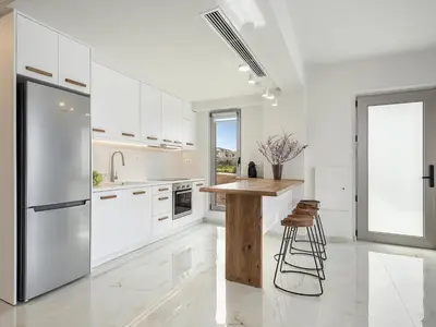 a kitchen with white cabinets and a wooden table at Fivi Villa, with Heated Pool & SeaViews, By ThinkVilla in Tavronitis