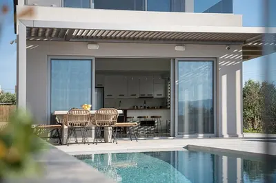 a patio with a table and chairs next to a pool at Fivi Villa, with Heated Pool & SeaViews, By ThinkVilla in Tavronitis