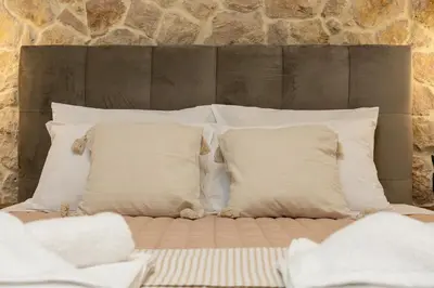 a bed with white pillows and a stone wall at Casa Dionysia - New Lux 2Br with Jacuzzi near Maleme Beach in Maleme