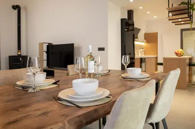 a wooden table with chairs and wine glasses on it at Casa Dionysia - New Lux 2Br with Jacuzzi near Maleme Beach in Maleme