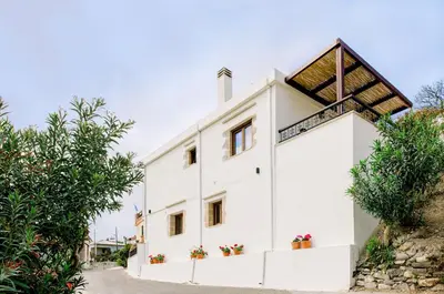 a white house with a roof on top of it at Alonion Apartments in Yerakianá