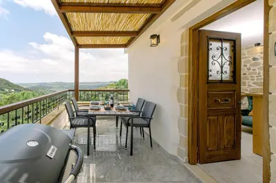 a patio with a table and chairs on a balcony at Alonion Apartments in Yerakianá