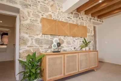 a stone wall in a kitchen with a wooden cabinet at Elirion Luxury Home in Kamária