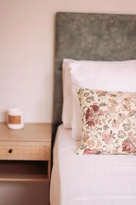 a bed with a pillow and a wooden night stand at Summer Blue Apartments Chania in Chania Town