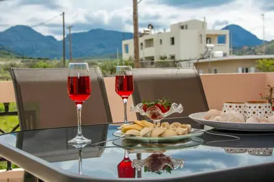 a table with two glasses of wine and a plate of food at Jasmine House Kissamos in Kissamos
