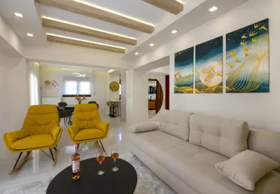 a living room with a white couch and yellow chairs at Aretousa Home in Chania Town
