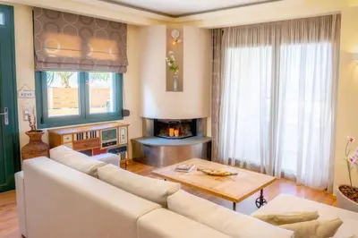 a living room with a white couch and a fireplace at Deja Blue Chania in Daratso