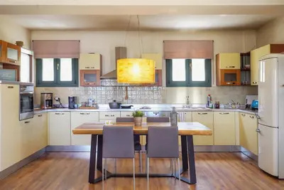 a large kitchen with a wooden table and chairs at Deja Blue Chania in Daratso