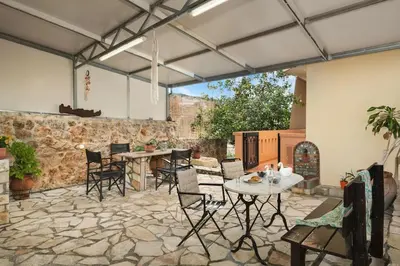 a patio with a table and chairs on a stone floor at Villa Androniki in Souda