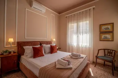 a bedroom with a bed and a chair and a window at ANMI Hospitality in Chania Town
