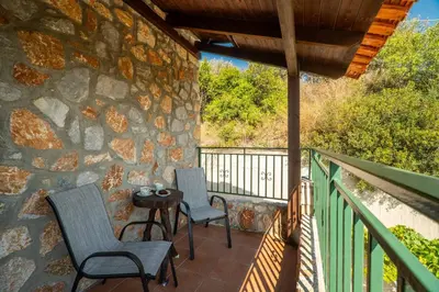 a patio with two chairs and a table on a stone wall at Agnadia Villa in Stalos