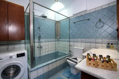 a bathroom with a washing machine and a bath tub at G & E Apartment in Kissamos
