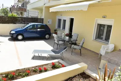 a blue car parked next to a house with a table and chairs at Eleni's Σπίτι μπροστά στη θάλασσα in Daratso